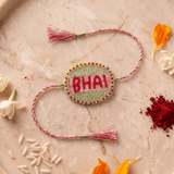 Beautifull handcrafted Green and Silver Embroidered Rakhi with Pink Braded Thread Tassels - Western Era Rakhi for women