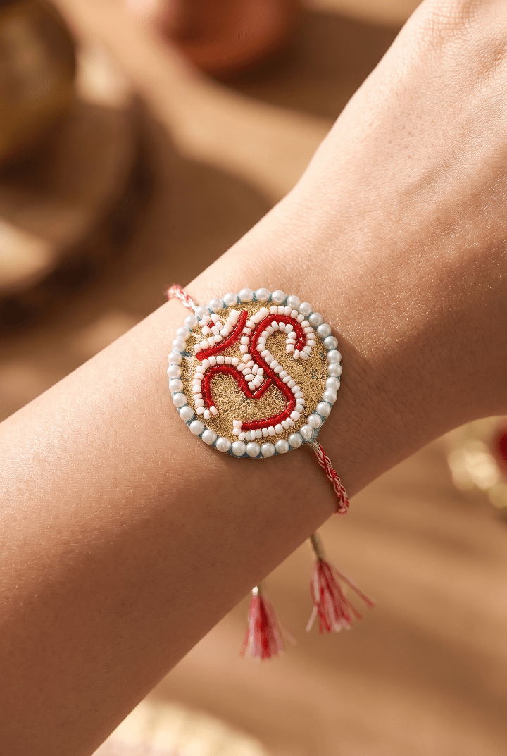 Om Motif Embellished with Red, White, and Golden Beadwork Rakhi - Western Era Rakhi for women